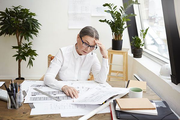 woman looking stressed at blueprints